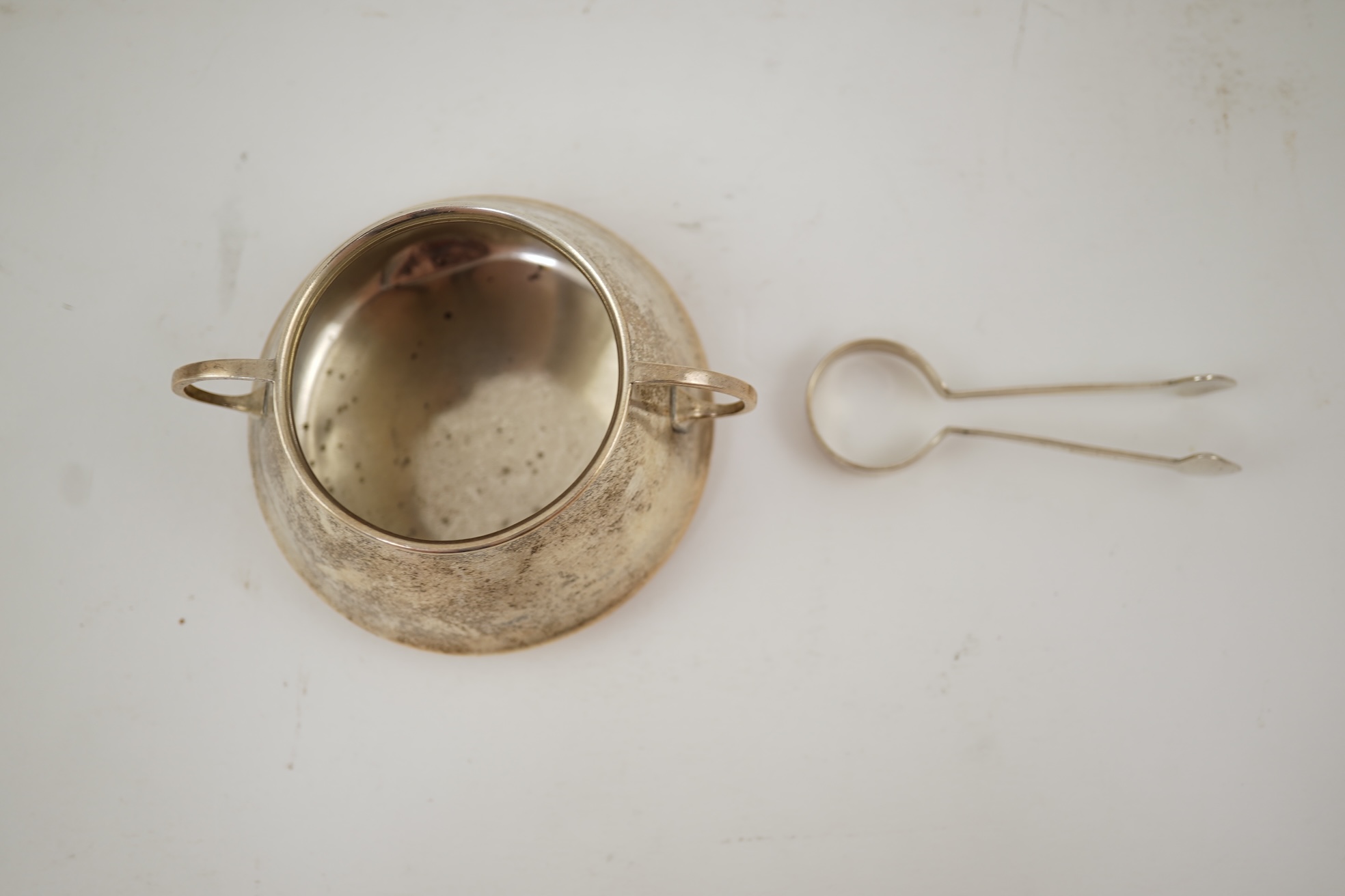 An Edwardian silver bachelor's two handled sugar bowl and matching sugar tongs, by Liberty & Co